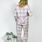 Girl wearing a pink and gray plaid pyjama set with two wrapped gifts on a white background