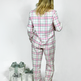 Girl wearing a pink and gray plaid pyjama set with two wrapped gifts on a white background