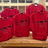 Red kids hoodies with a logo and 'Banff Canada' text on a wooden table. Showing the various kids sizes.