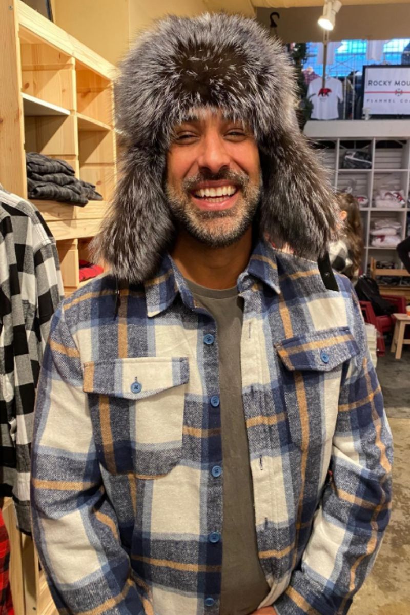 Man wearing a fur hat and plaid jacket in a store setting