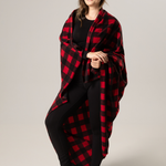 Woman wearing a red and black buffalo check blanket against a plain background