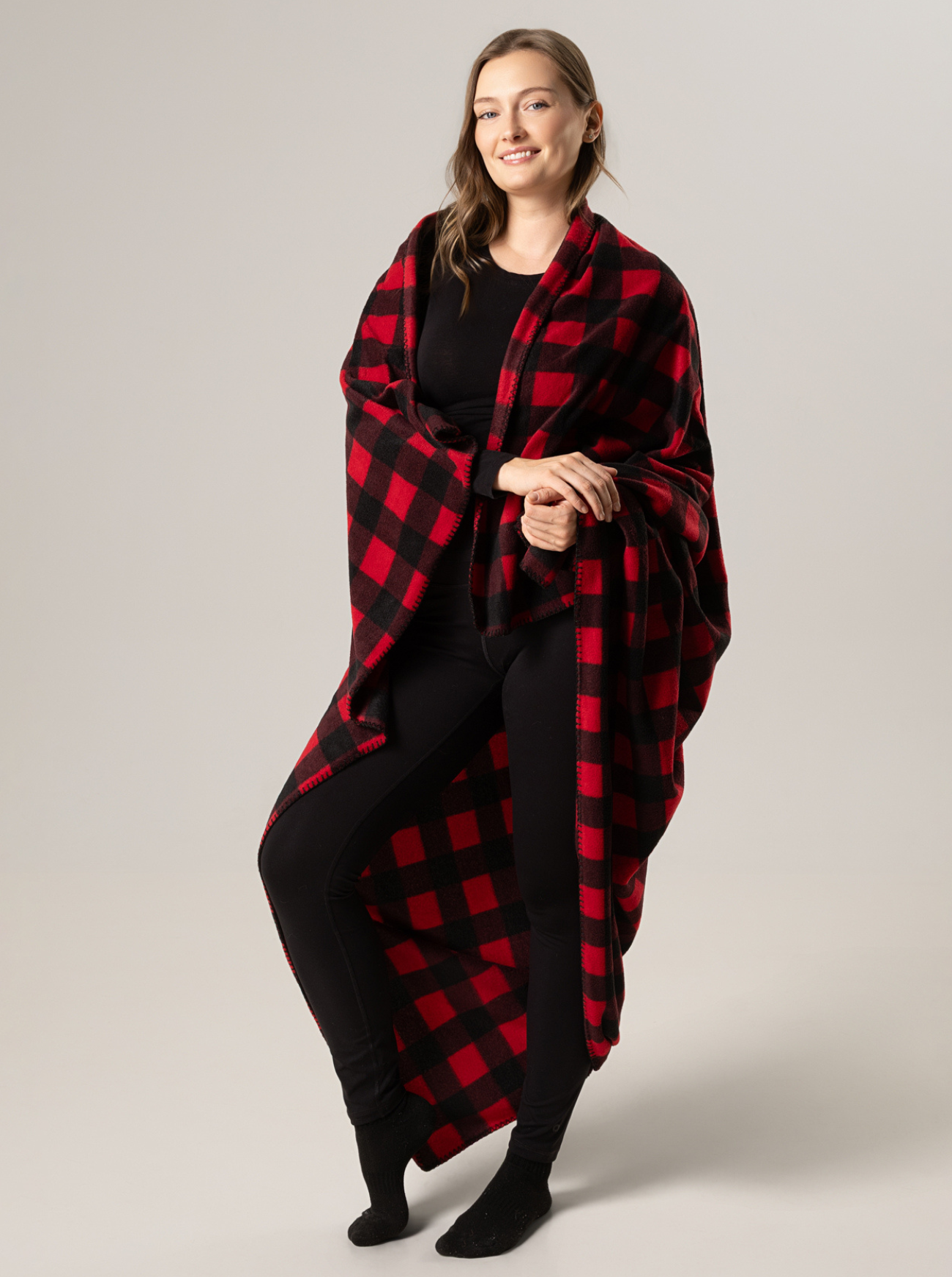 Woman wearing a red and black buffalo check blanket against a plain background