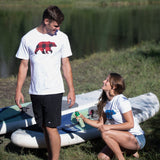 Two people with inflatable kayaks in a grassy outdoor setting