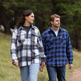 A man wearing a royal blue and black buffalo check padded flannel camping outdoor jacket with jeans.
