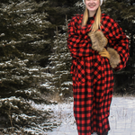 Person wearing a red and black checkered robe in a snowy forest.