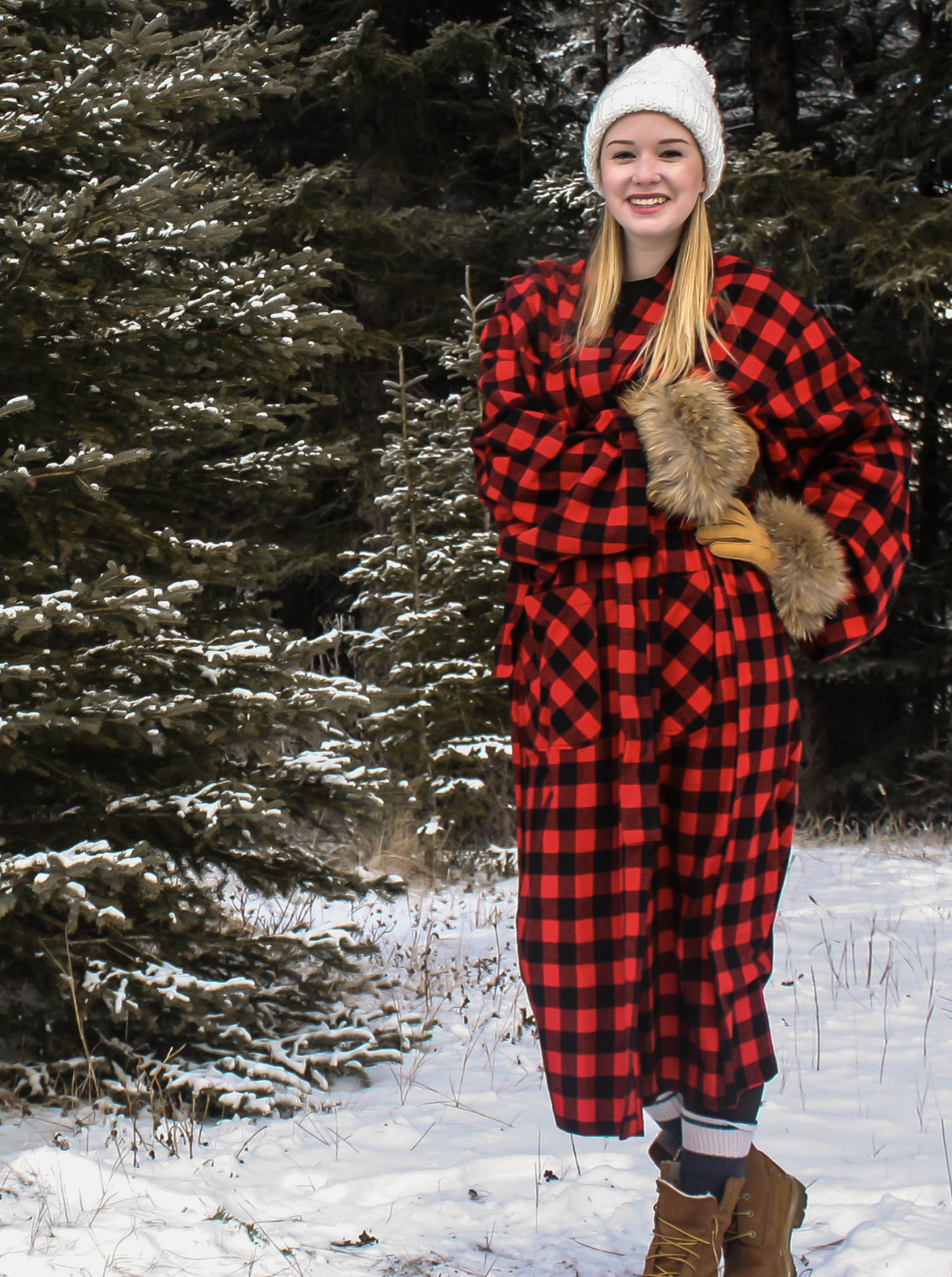 Person wearing a red and black checkered robe in a snowy forest.