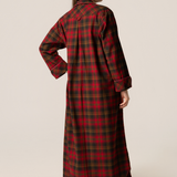 Person wearing a red and green plaid dress against a beige background