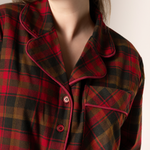 Close-up of a person wearing a maple leaf tartan nightshirt with a neutral background