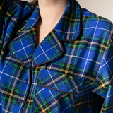 Close-up of a person wearing a blue plaid nightgown with a neutral background