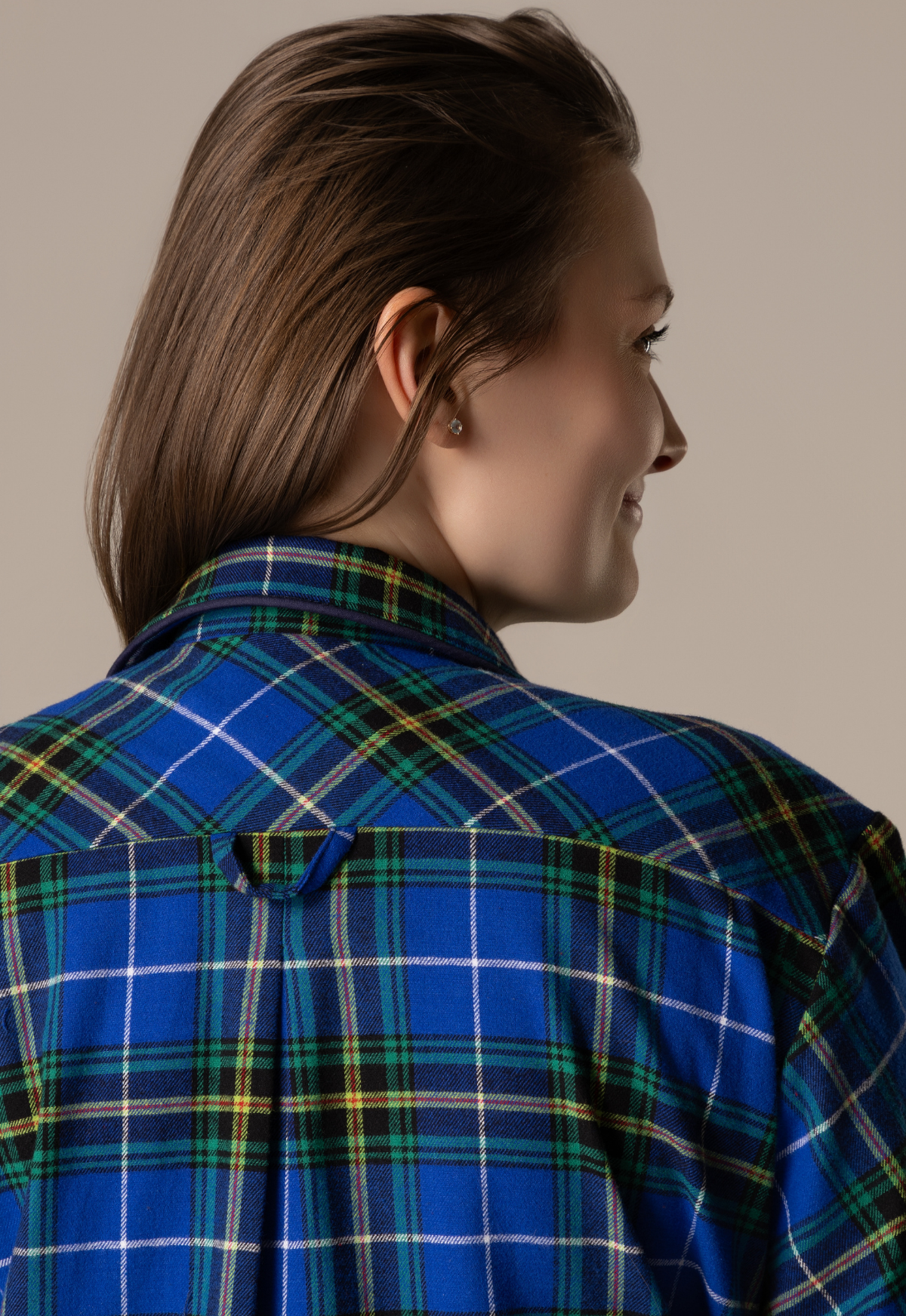 Person wearing a blue plaid nightgown against a neutral background