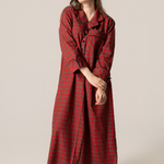 Woman wearing a red plaid nightgown against a plain background