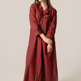 Woman wearing a red plaid nightgown against a plain background