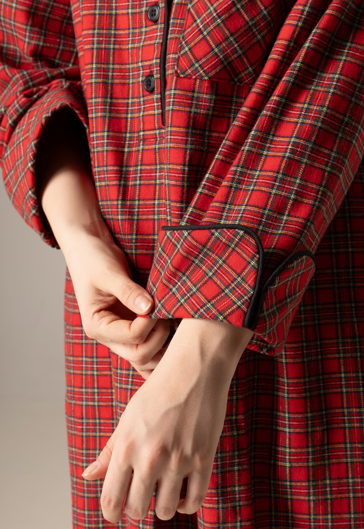 Red plaid nightgown with a close-up of hands adjusting the cuff against a neutral background