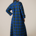 Person wearing a blue plaid nightgown against a beige background
