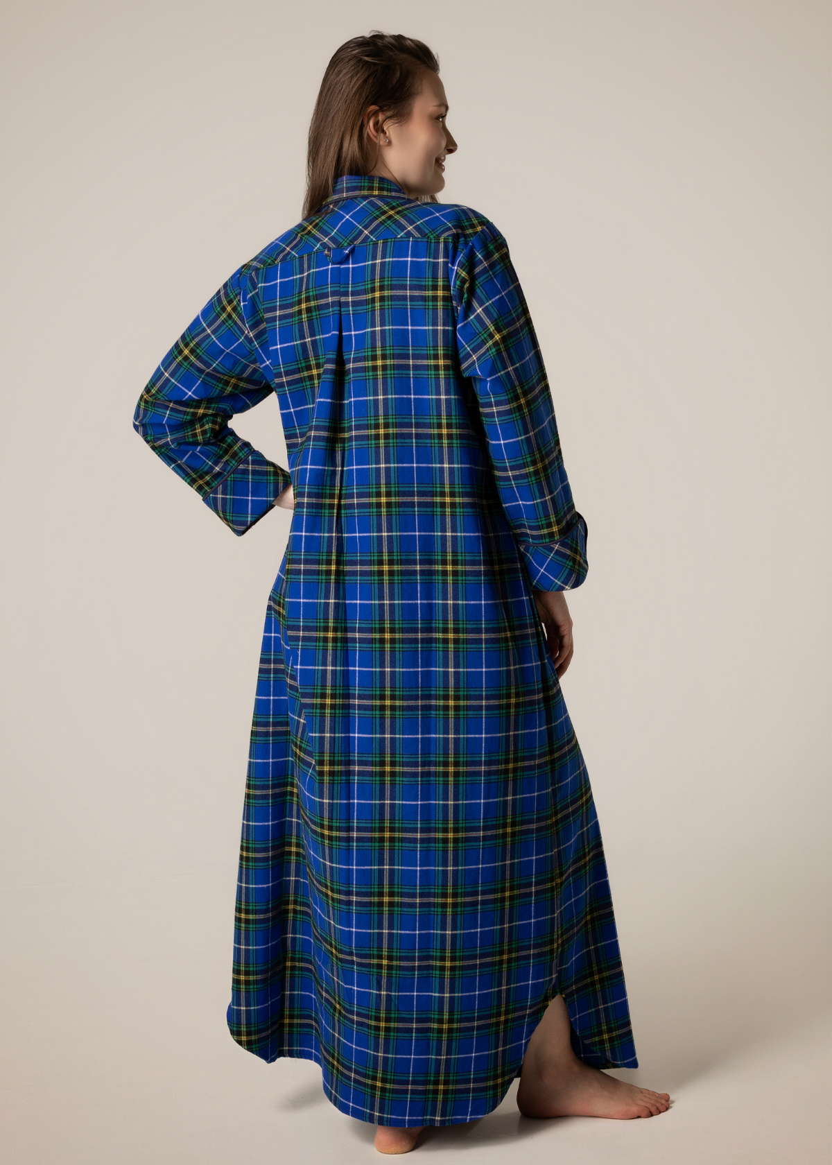 Person wearing a blue plaid nightgown against a beige background