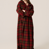 Woman wearing a long maple leaf tartan nightshirt on a beige background