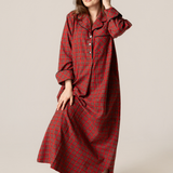 Woman wearing a red plaid nightgown against a plain background