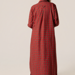 Person wearing a red plaid flannel nightgown against a beige background