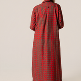 Person wearing a red plaid flannel nightgown against a beige background