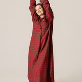 Woman wearing a red checkered dress against a beige background