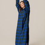 Person wearing a blue plaid nightgown against a beige background