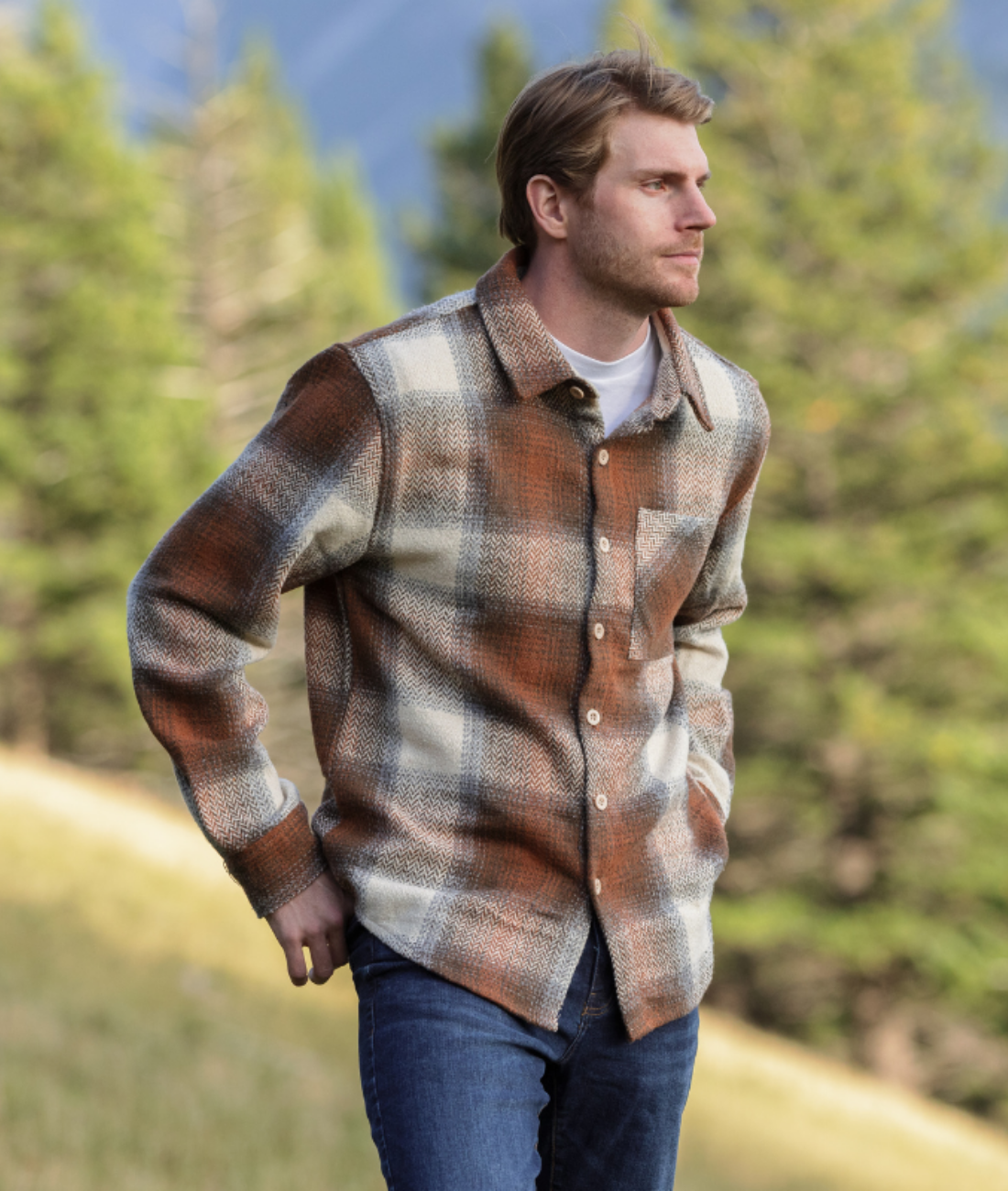 Man wearing a plaid shacket in a forest setting