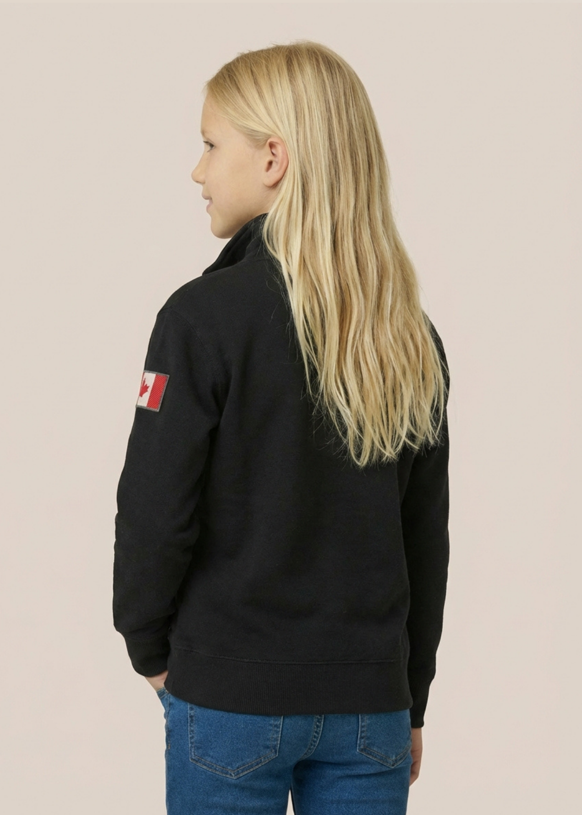 Person wearing a black jacket with a flag patch on the back against a beige background