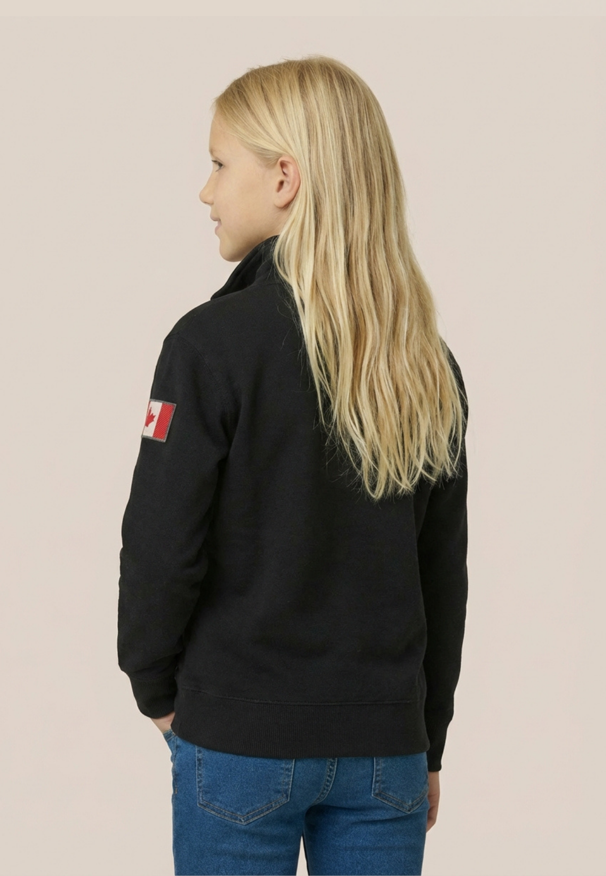 Person wearing a black jacket with a flag patch on the back against a beige background