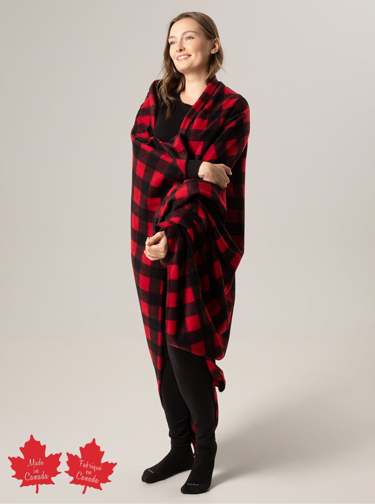 Woman wearing a red and black checkered blanket over her shoulders with 'Made in Canada' logos at the bottom.