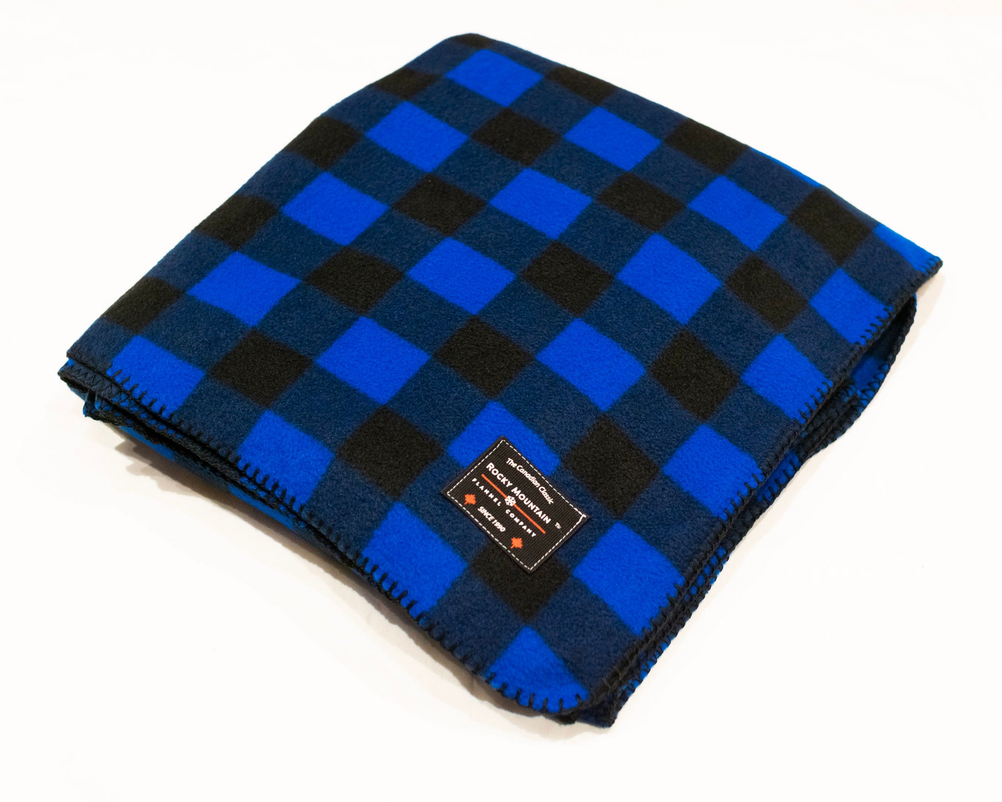 A blue and black checkered fleece blanket laid out on a white background, with a small branded tag visible.