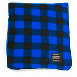A blue and black checkered fleece blanket with a label showing the brand name and Canadian-made status.