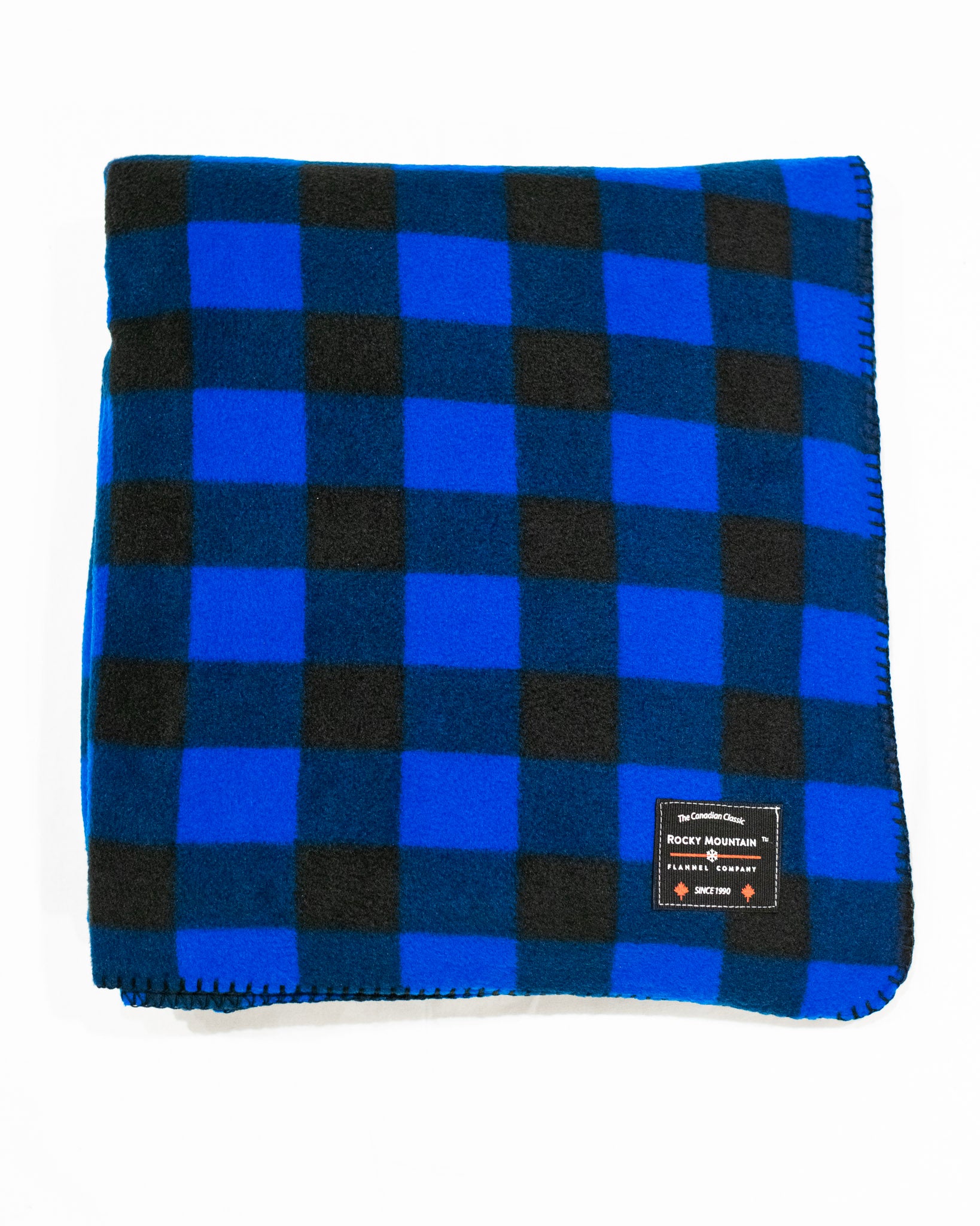 A blue and black checkered fleece blanket with a label showing the brand name and Canadian-made status.