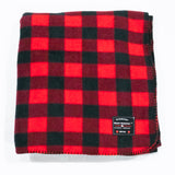 A red and black buffalo check fleece blanket with a label showing the brand name.